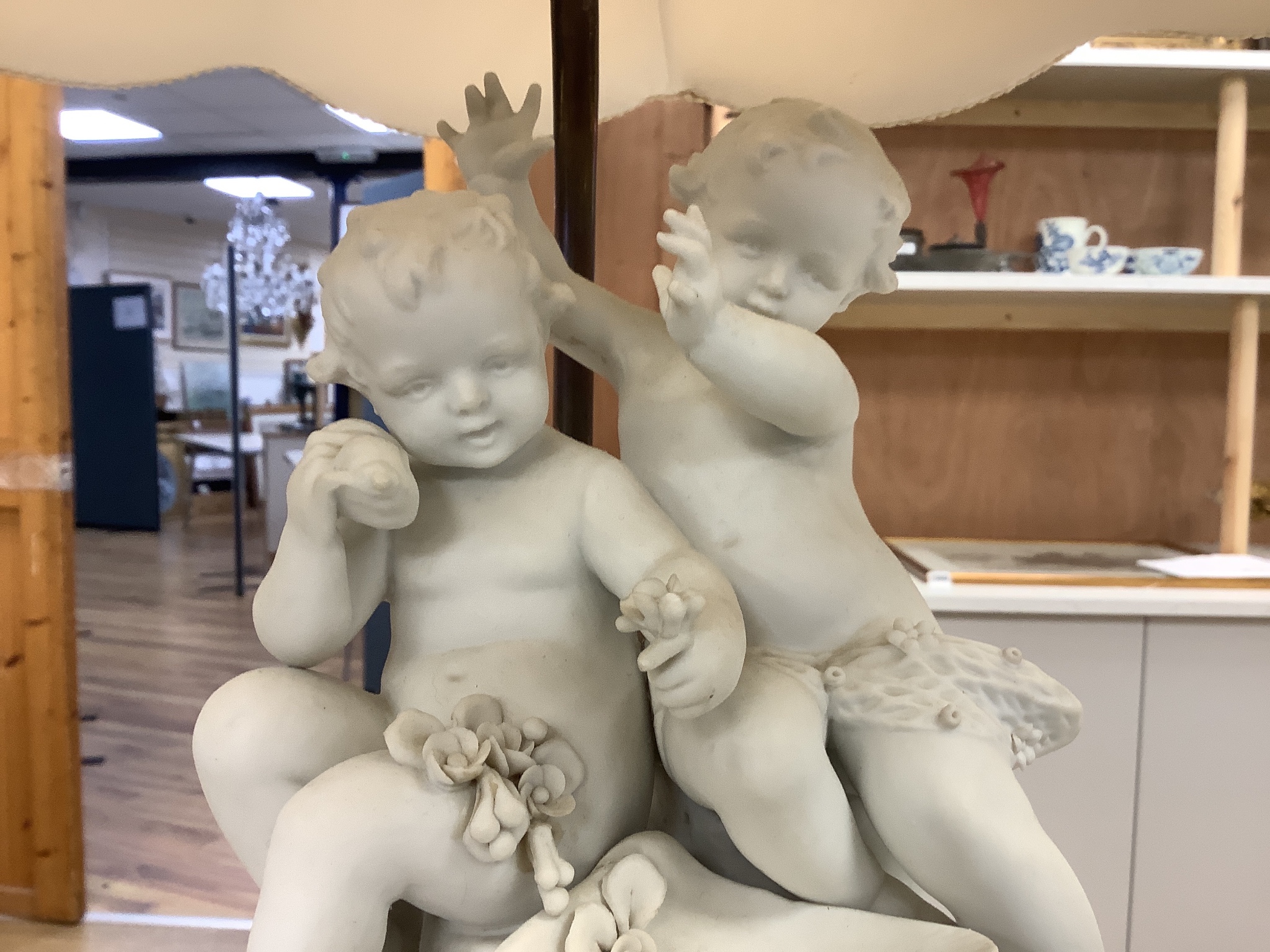 A pair of Sevres style biscuit porcelain groups of putti, fitted as a table lamps with shades 69cm total height incl shades